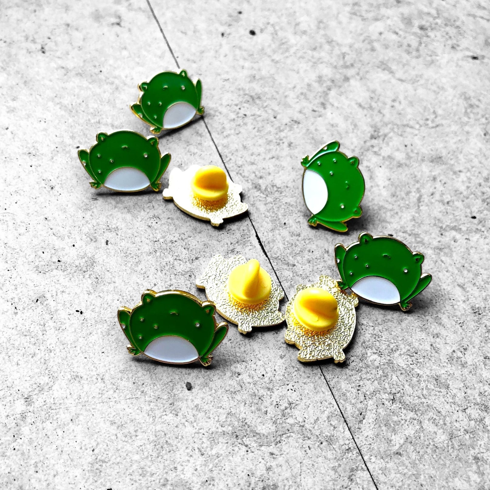 a bunch of angry frog pins, showing front and back, with yellow rubber backing