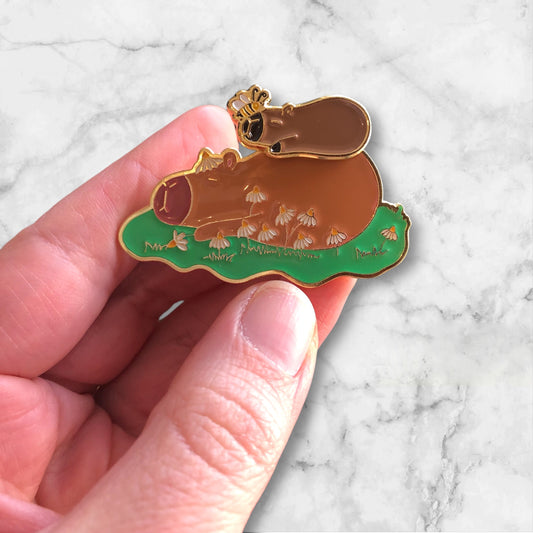 capybara pin with magnetic baby capybara in hand, against a marble background
