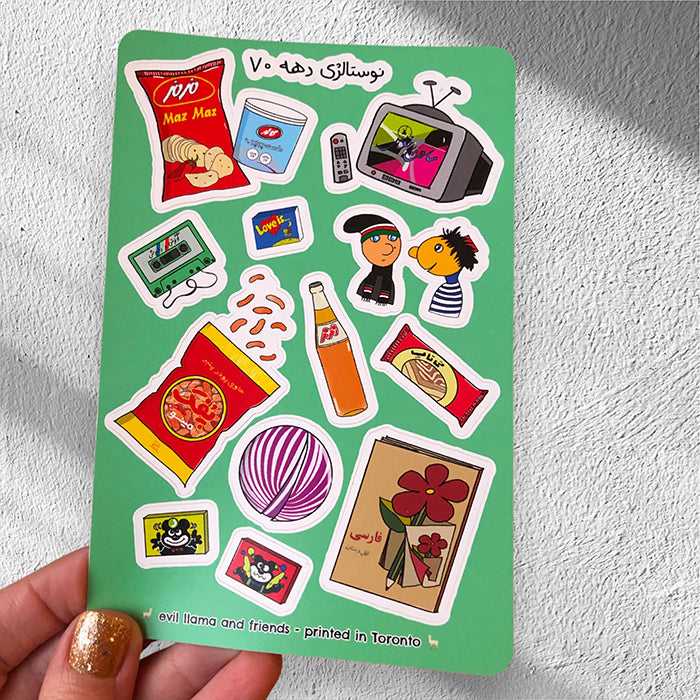 one sticker sheet in hand, held against a white wall with a shadow. the sticker sheet is composed of 90s nostalgic elements from iran such as zam zam soda bottle, a bag of maz maz chips, and kolah ghermezi and pesar khaleh