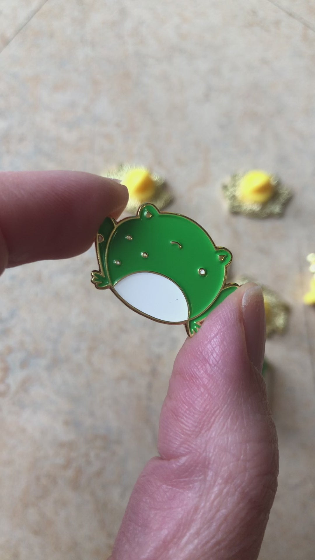 angry frog pin in hand, showing front and back