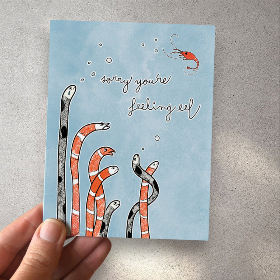 sorry you're feeling eel sympathy card in hand, against a white wall with shadows. perfect for anyone going through a tough time, in need of a laugh