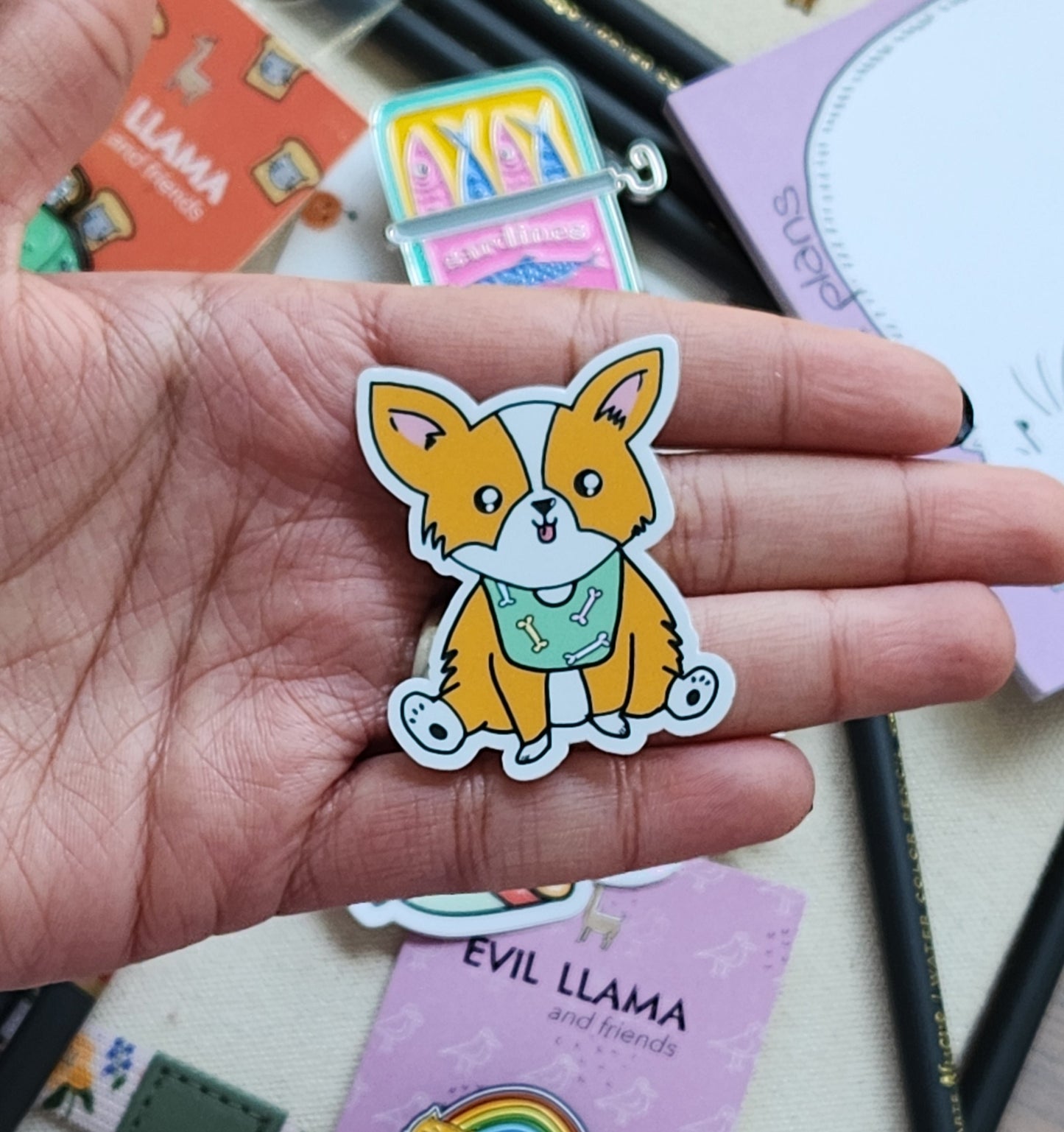 Hand holding a cartoon corgi sticker with a colourful background