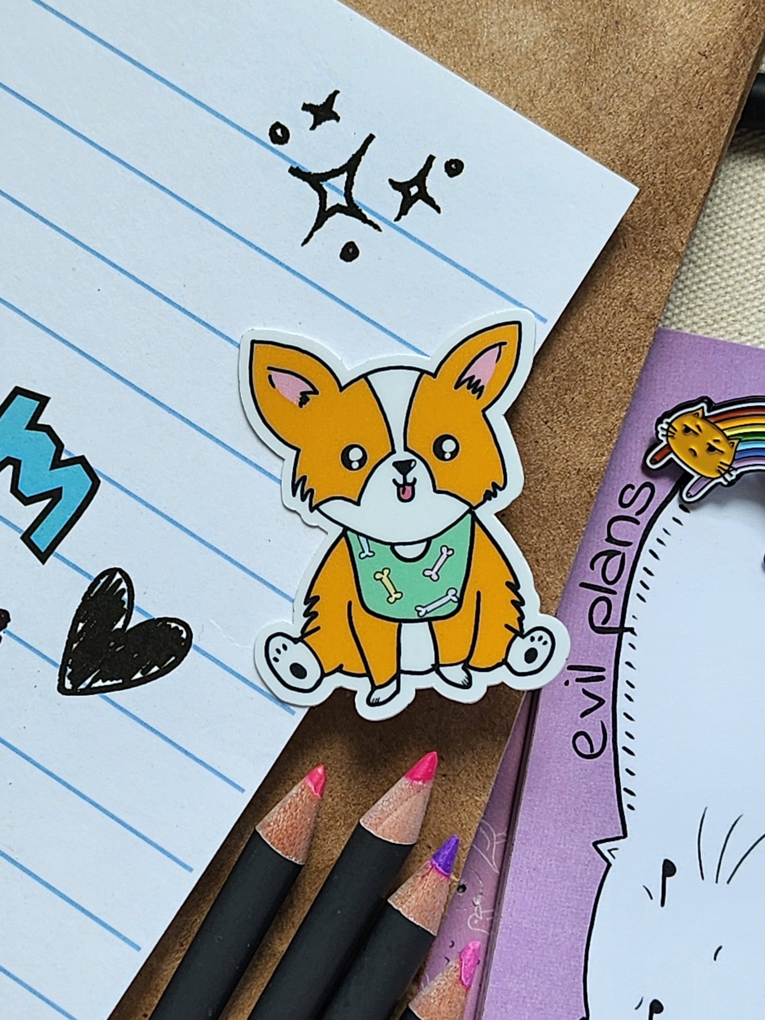 Cartoon dog sticker on lined paper with pencils and a notepad in the background