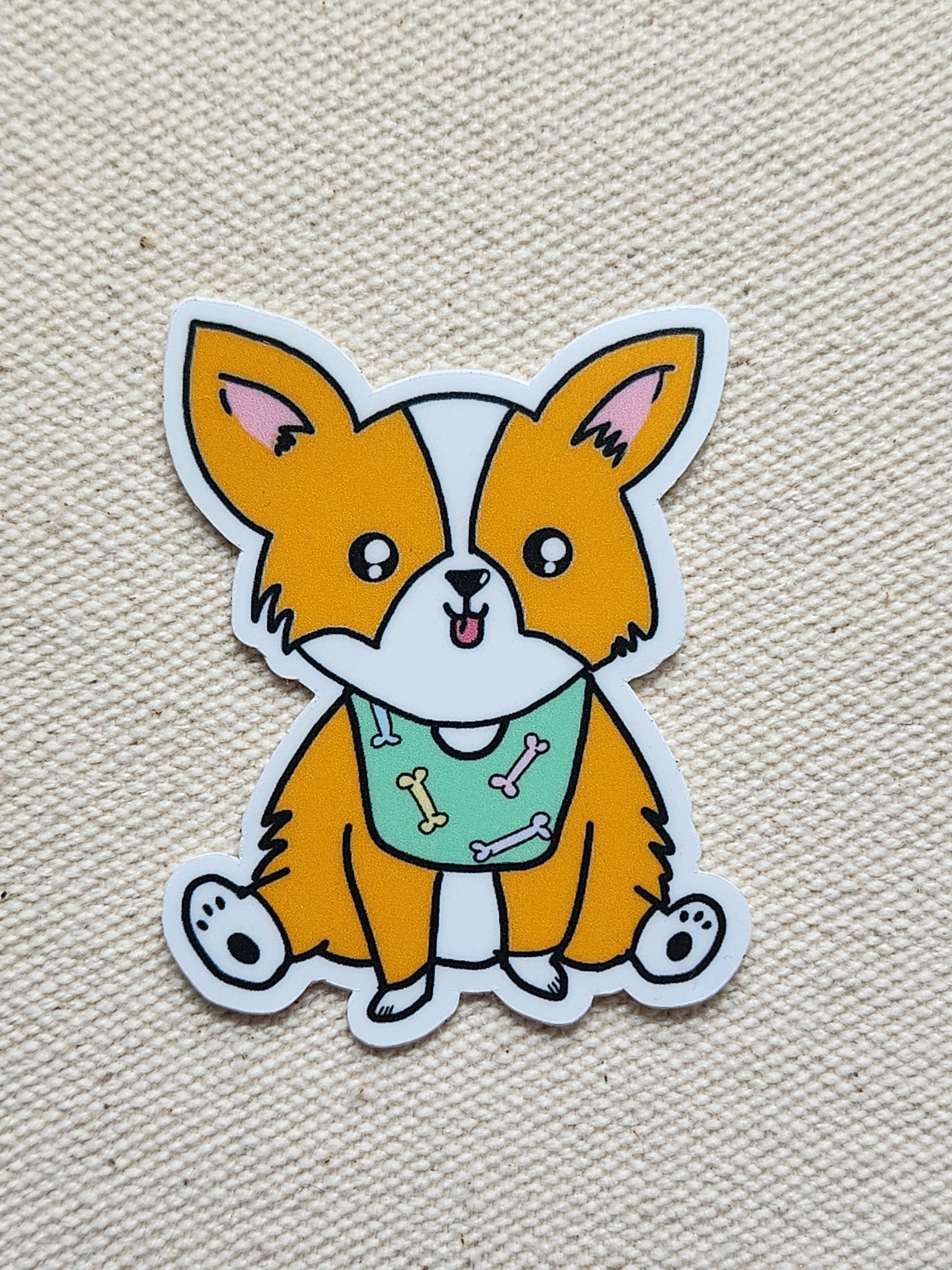 Cartoon dog sticker with a green bib on a beige textured background