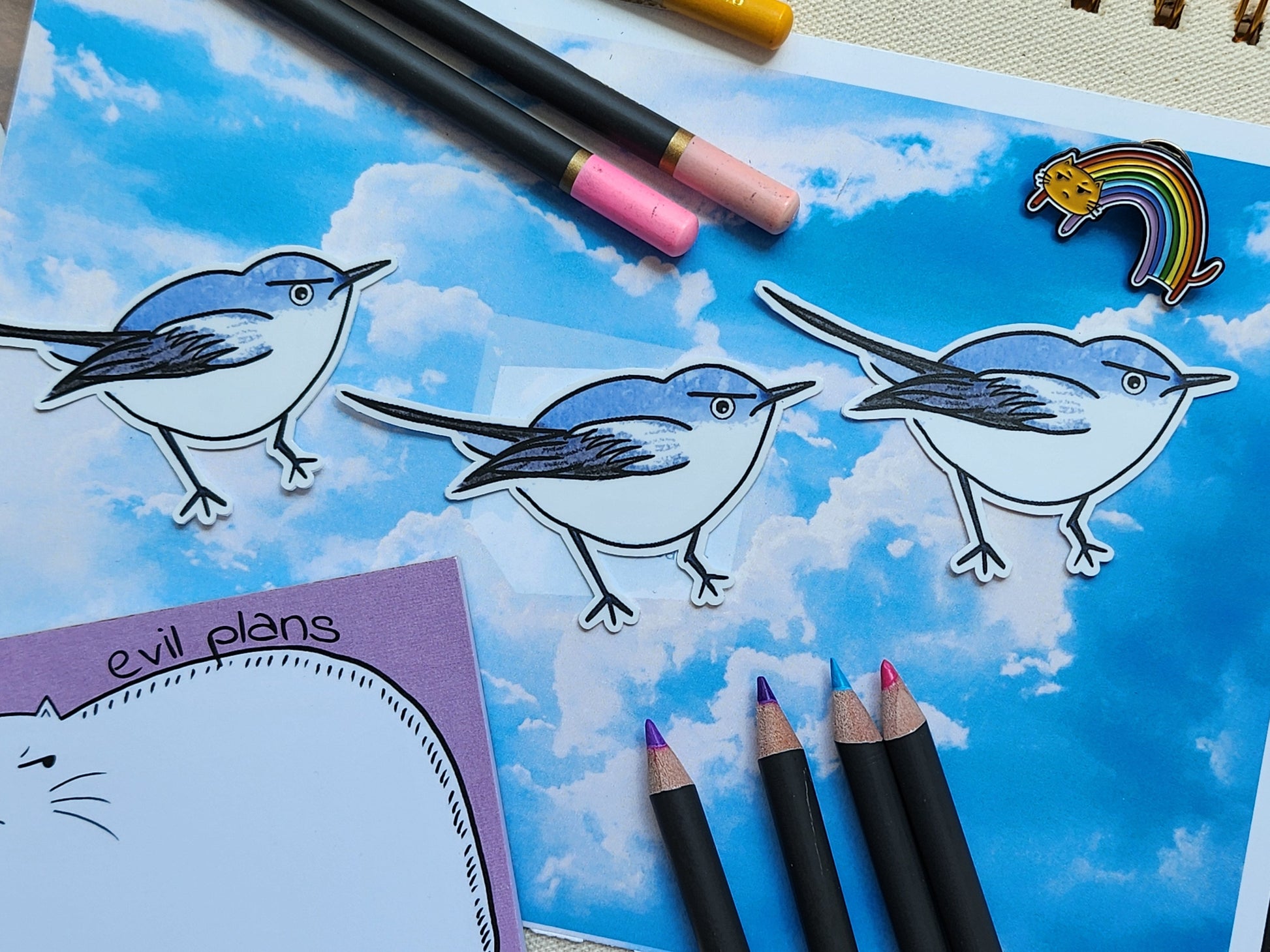 angry bird stickers on a blue sky background, next to coloured pencils and various stationery items