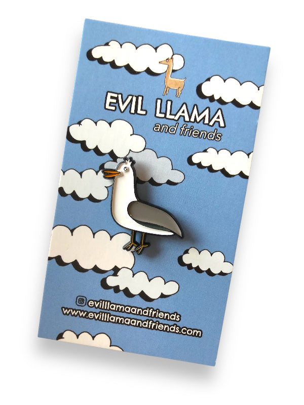 enamel pin of a funny looking gull on a backing card showing cartoon clouds and blue sky