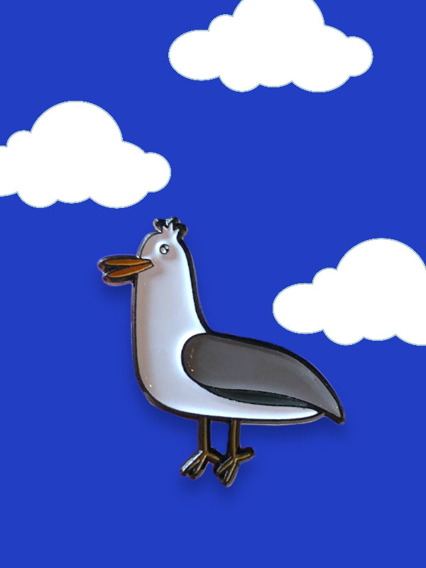 enamel pin of a cartoon gull against blue sky and white clouds