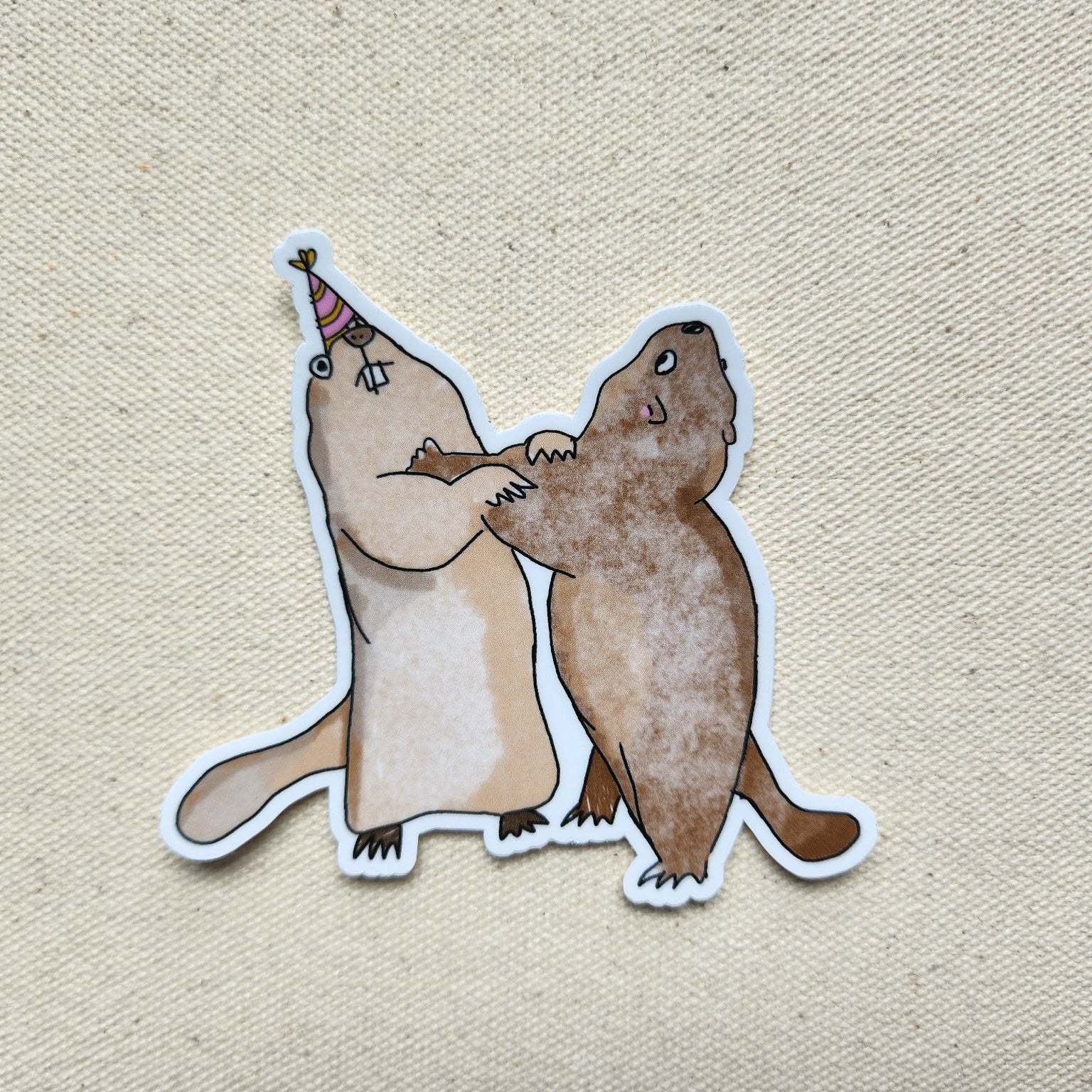sticker of 2 marmots with a party hat on a beige textured background