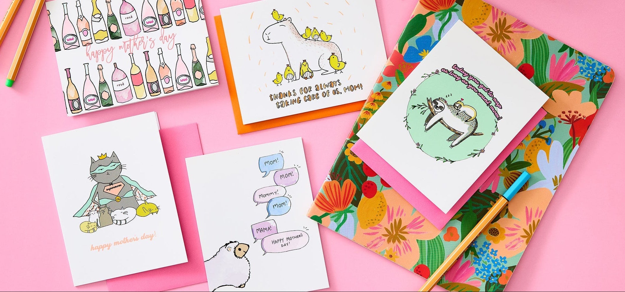 Collection of colorful greeting cards and stationery items on a pink background