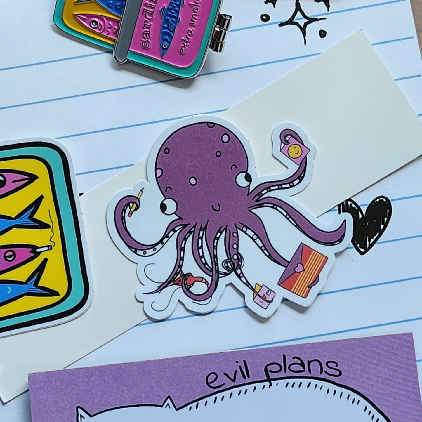 purple octopus sticker surrounded by stationery items, on a lined paper background.