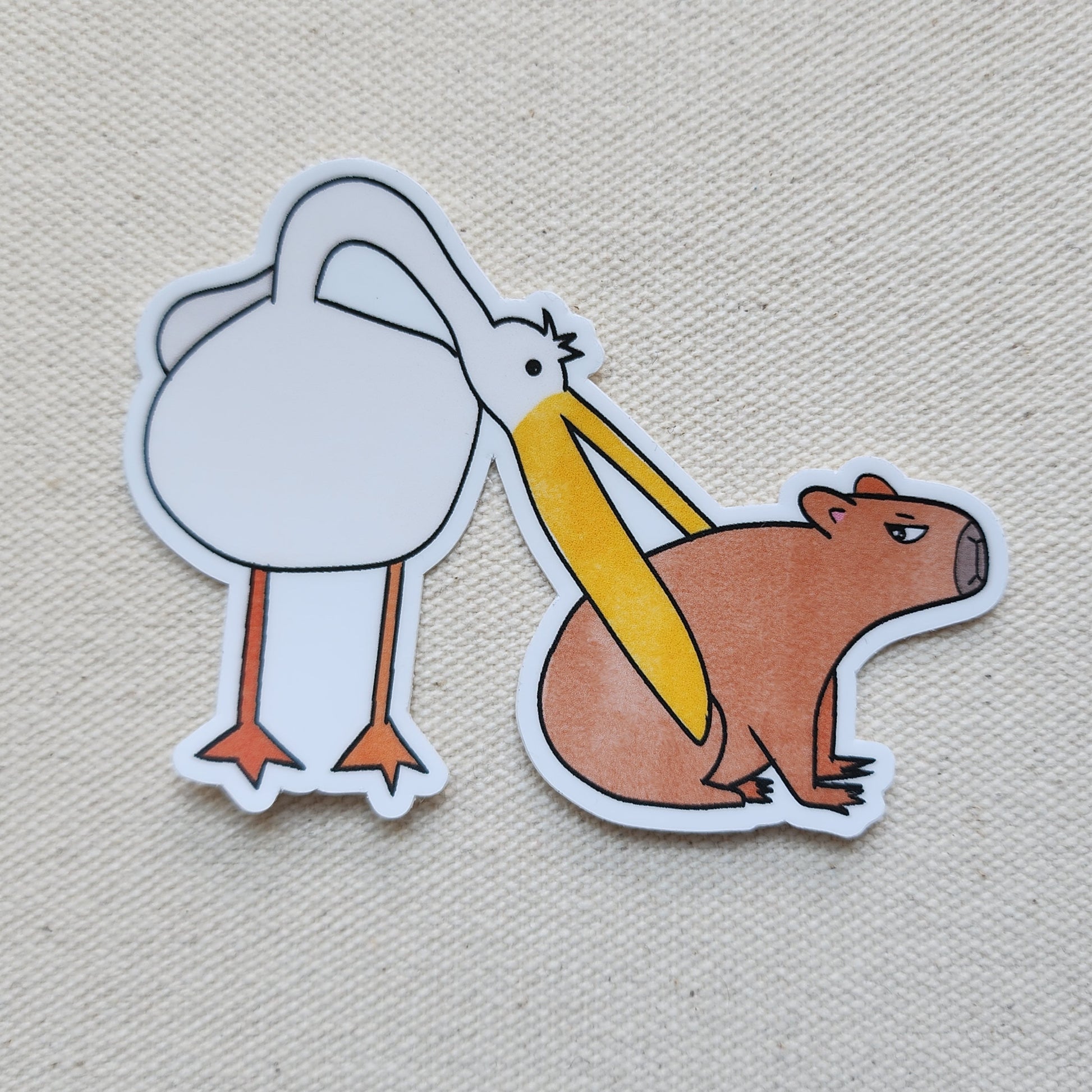 a sticker showing a pelican trying to eat a capybara, on a textured background