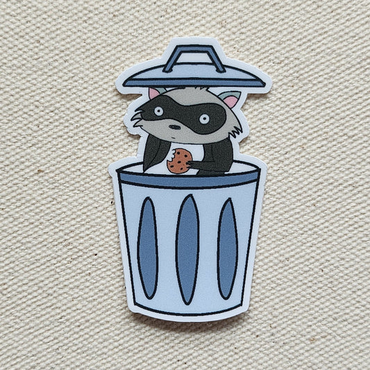 raccoon sticker in garbage can against a beige, textured background