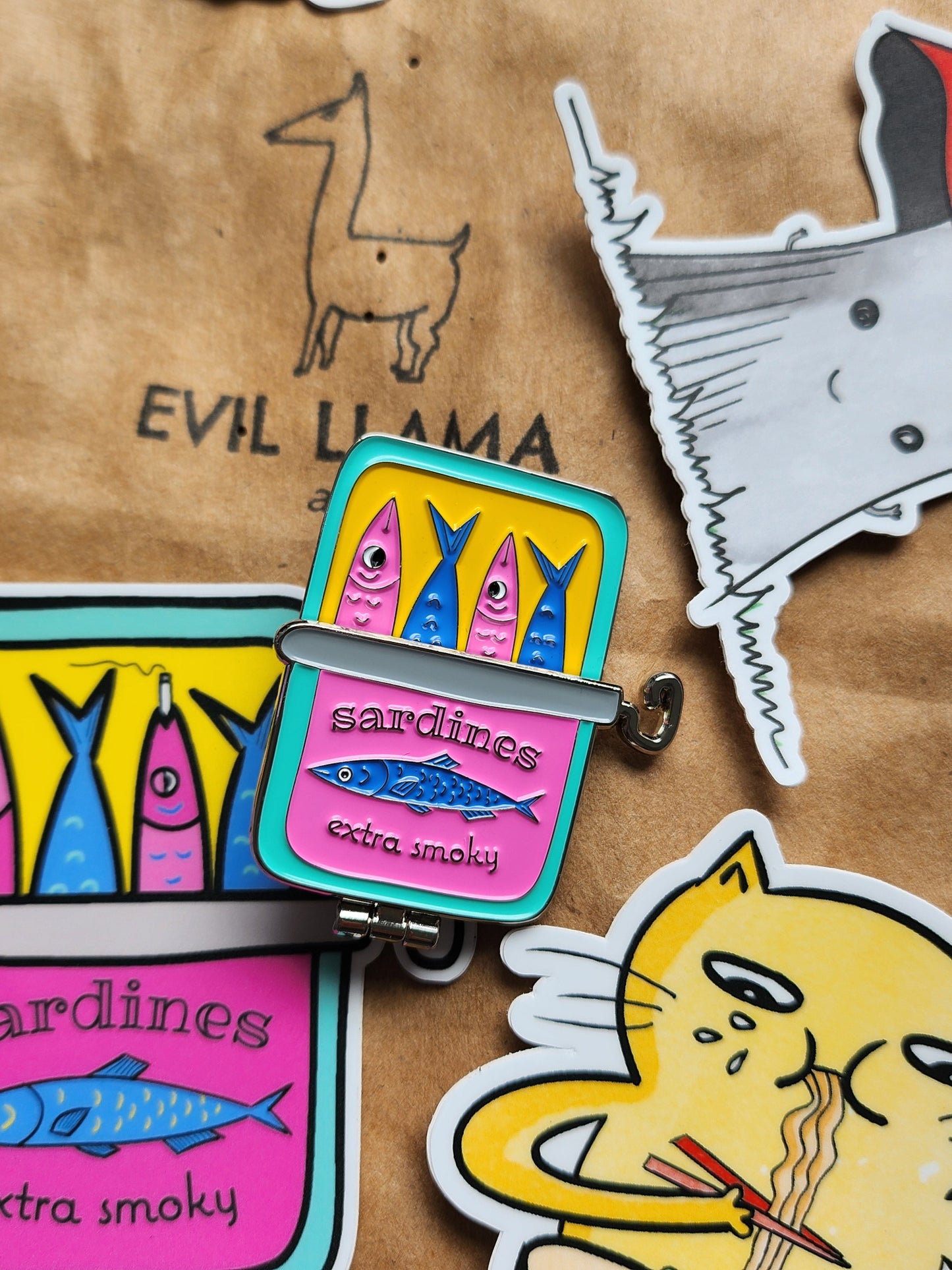sardine can pin styled on top of a craft paper bag, next to various stickers