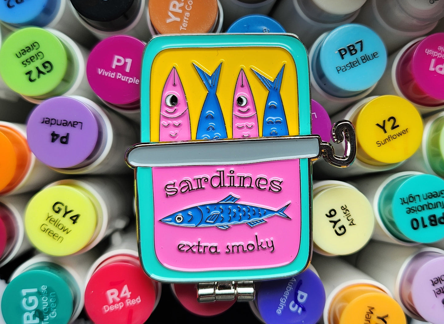 sardine can pin on top of colourful markers